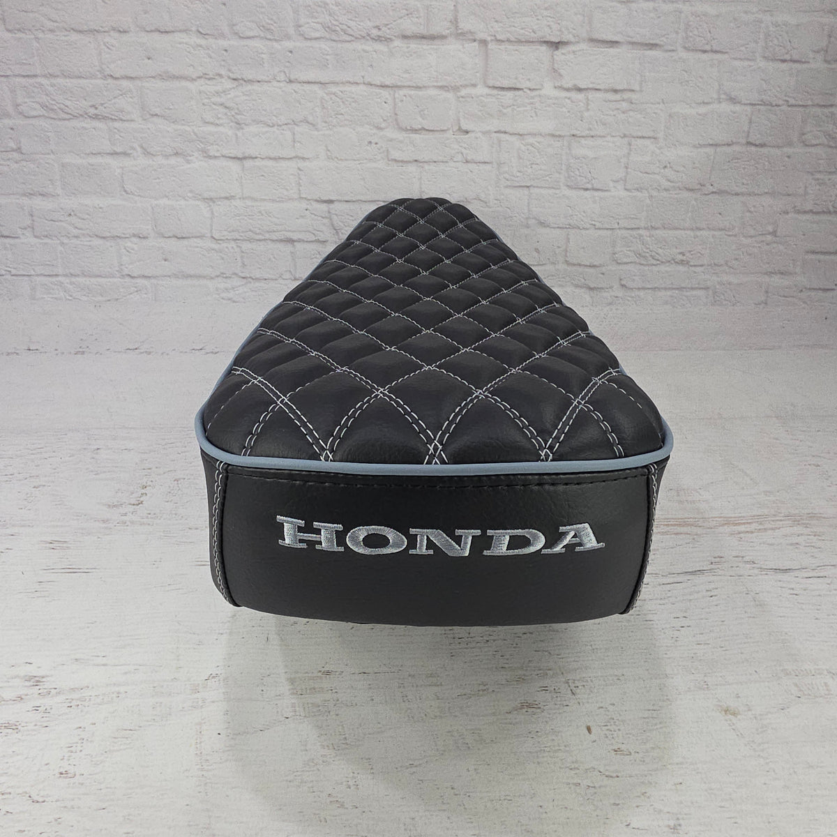 Rear view of a black double-diamond Honda DAX 125 cover with pale blue piping and silver Honda embroidery, handmade by Cheeky Seats