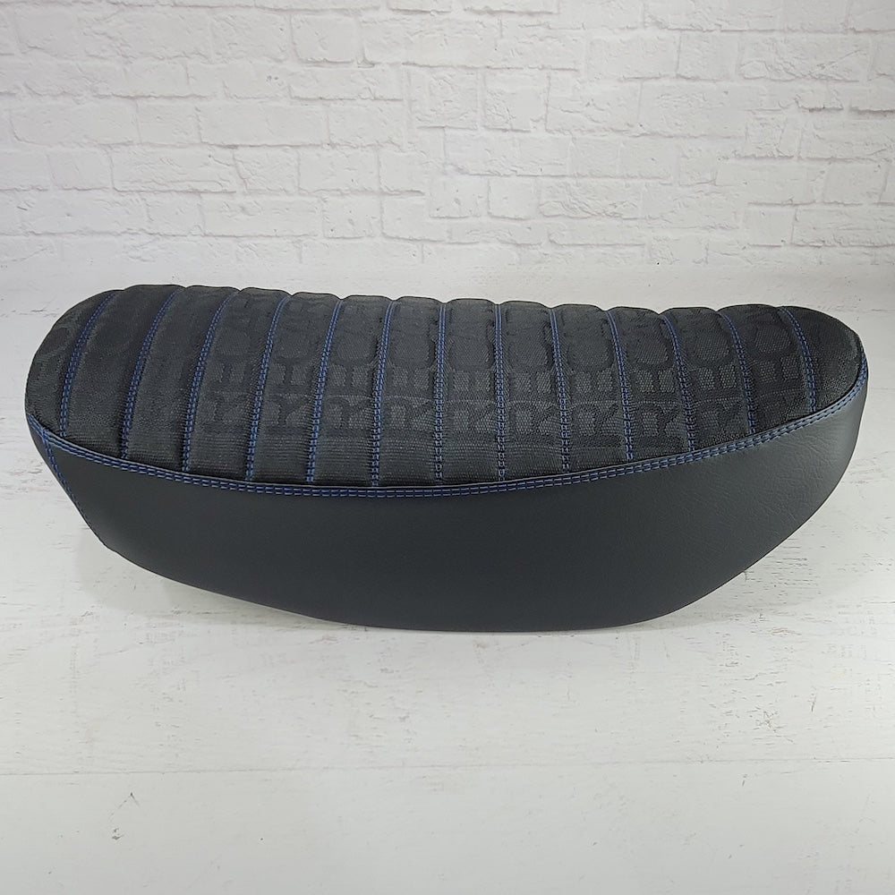 Side view of a black RECARO Honda DAX 125 cover with blue tuck-and-roll stitching and black side panels, handmade by Cheeky Seats