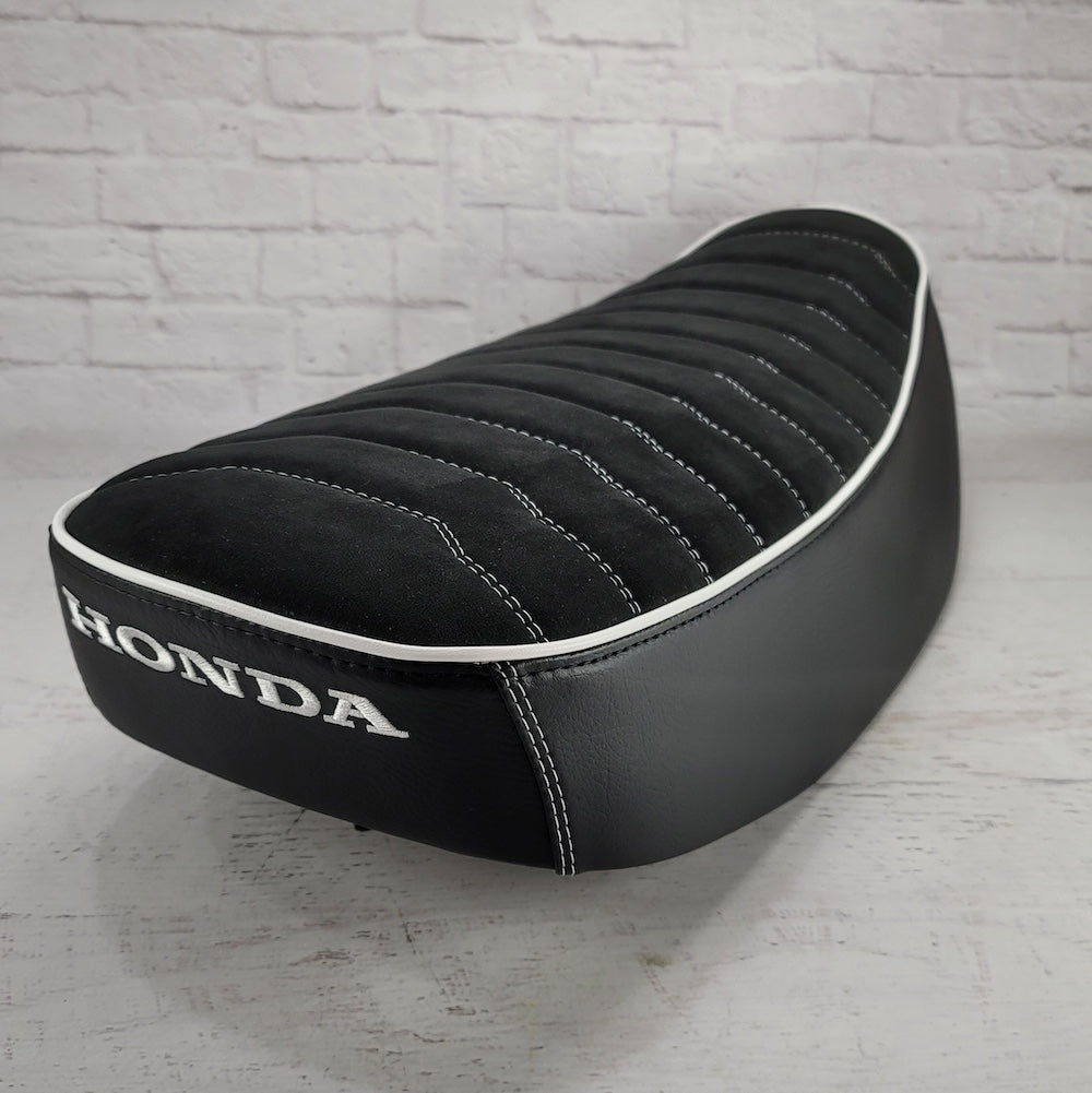 Rear view of a black Alcantara Rayas Honda DAX 125 cover with white piping and embroidered Honda logo, handmade by Cheeky Seats
