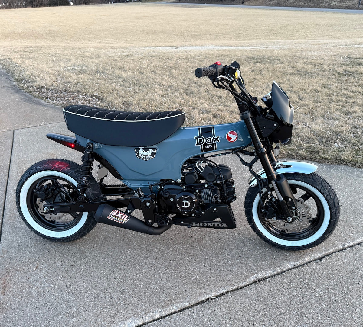 Custom Pearl Gray Honda DAX 125 with a black Alcantara Rayas seat, white piping, DAX and Honda logos, handmade by Cheeky Seats