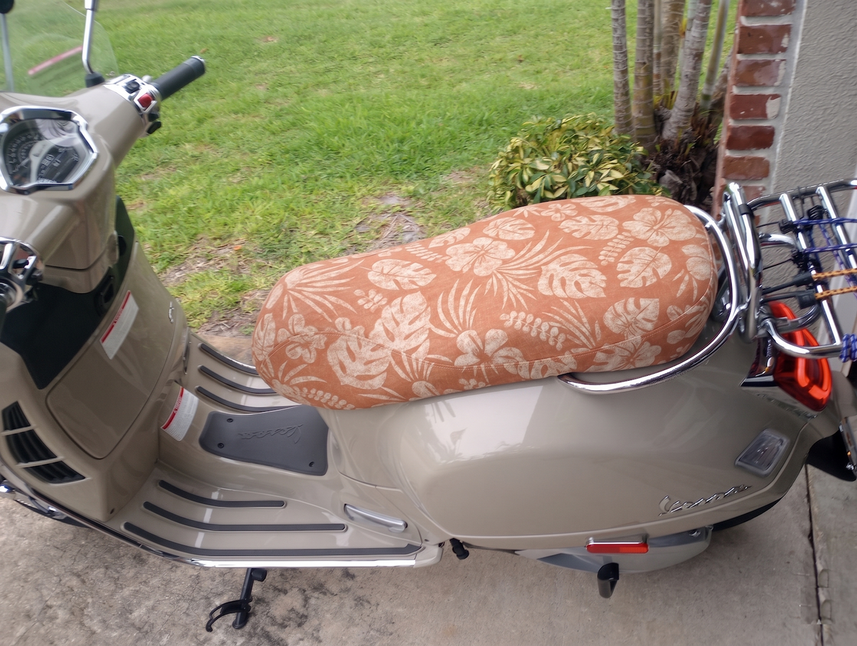 Terracoral Hibiscus seat cover fitted to a Vespa GTS, bringing a warm tropical finish to the scooter, handmade by Cheeky Seats.