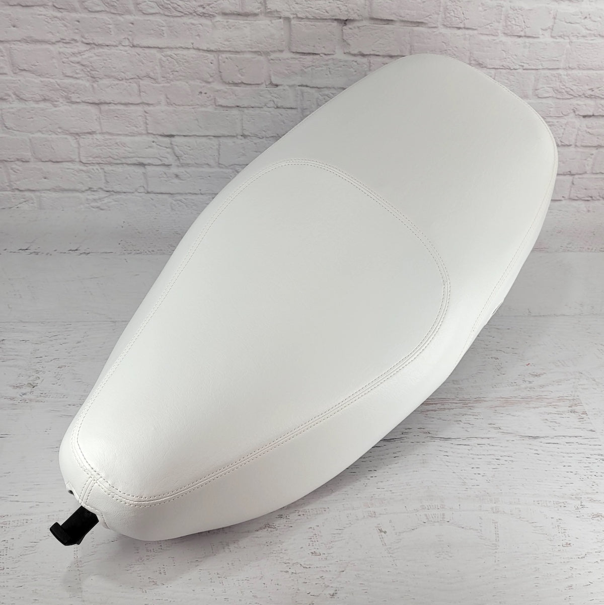 Top view of a Cottage White Vespa LX seat cover showing its sculpted center panel and tailored seams, handmade by Cheeky Seats.