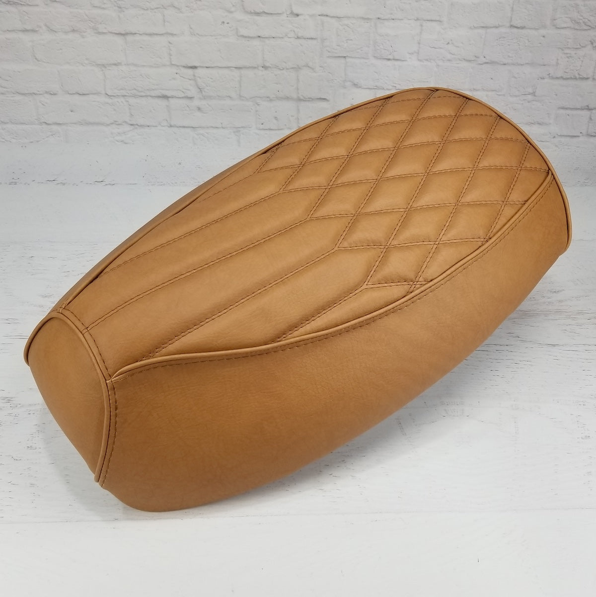 Side view of the Golden Tan Diamond Pleat Yamaha Vino 125 seat cover showing the sculpted center and tailored edge, handmade by Cheeky Seats.