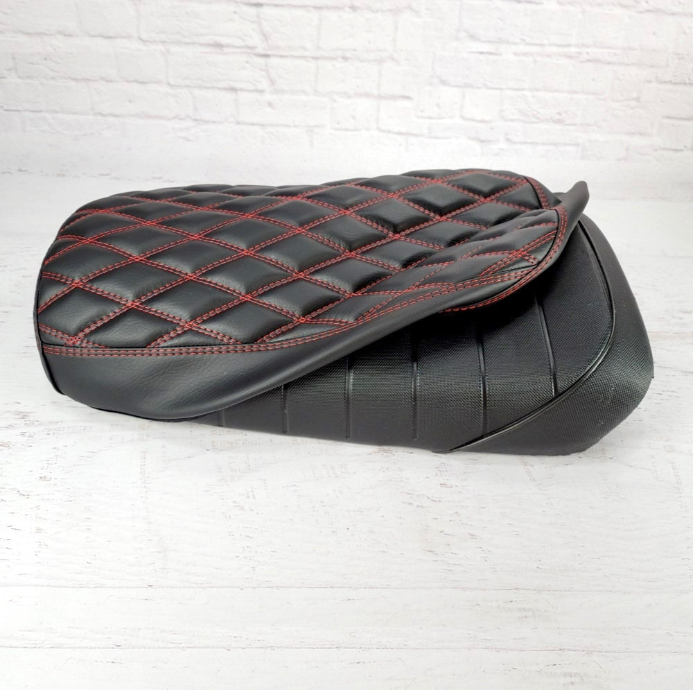 Black diamond-stitched seat cover with red stitching installed on the original Maddog seat, showing fitment