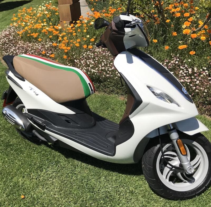 White Piaggio Fly scooter with a tan seat cover and Italian tricolor racing stripe, handmade by Cheeky Seats