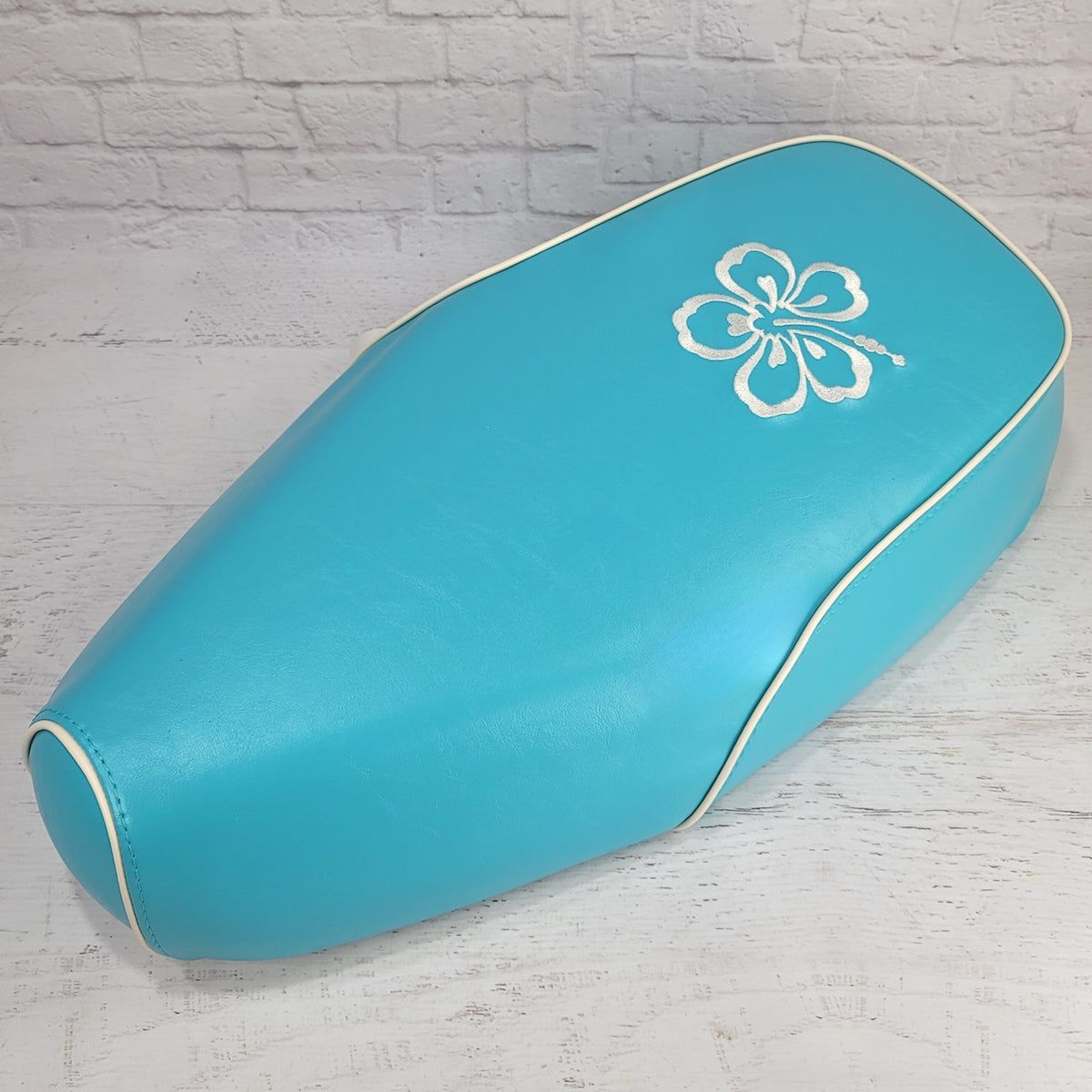 Turquoise Genuine Buddy Kick 125 seat cover with cream piping and white hibiscus embroidery, handmade by Cheeky Seats