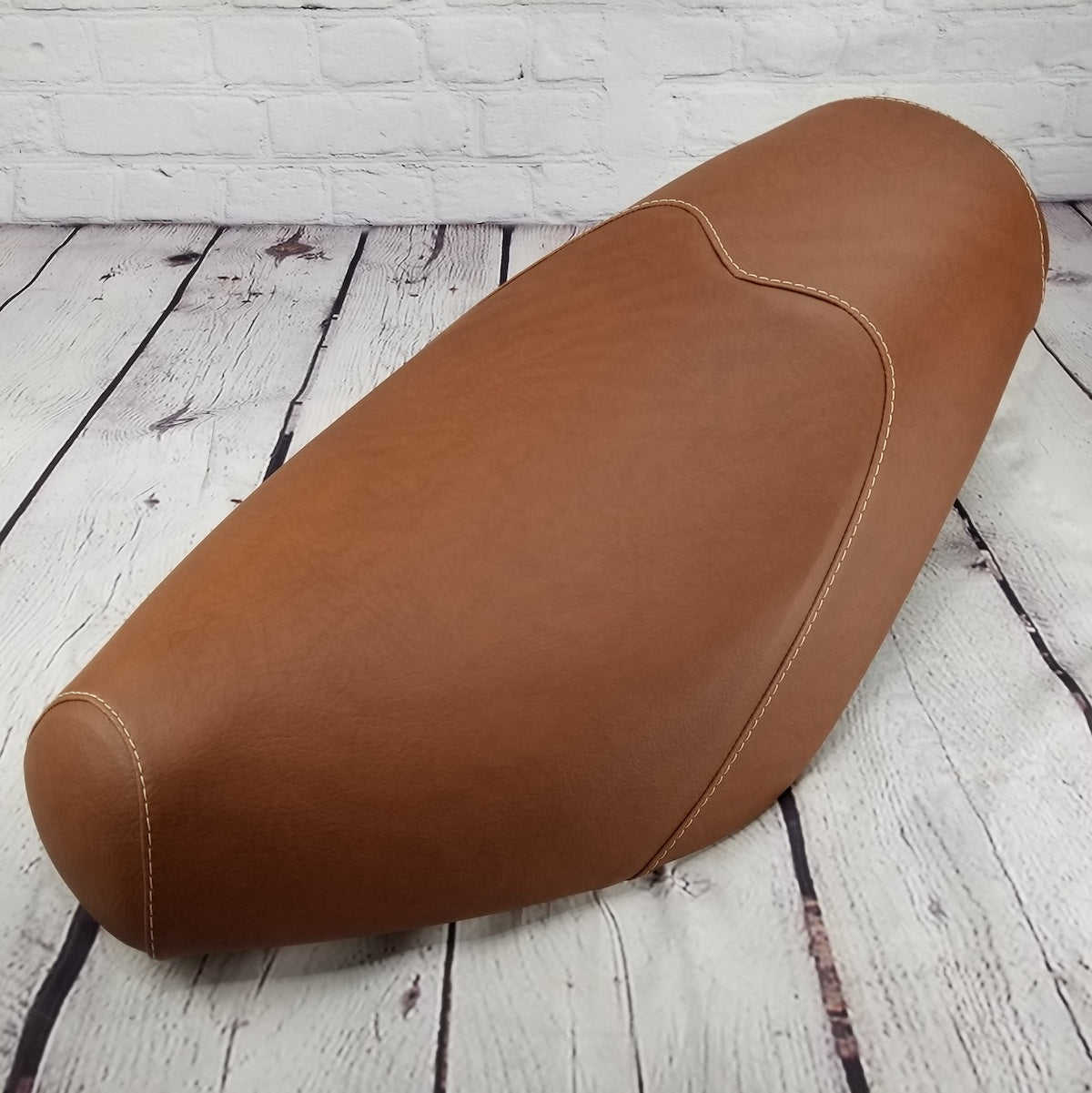 Cinnamon-brown Cheeky Seats cover shaped for a Genuine Buddy low-profile seat, front-left view