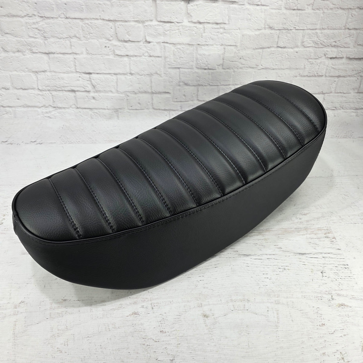 Black-on-black tuck-and-roll Honda DAX 125 seat cover with matching stitching and piping, handmade by Cheeky Seats