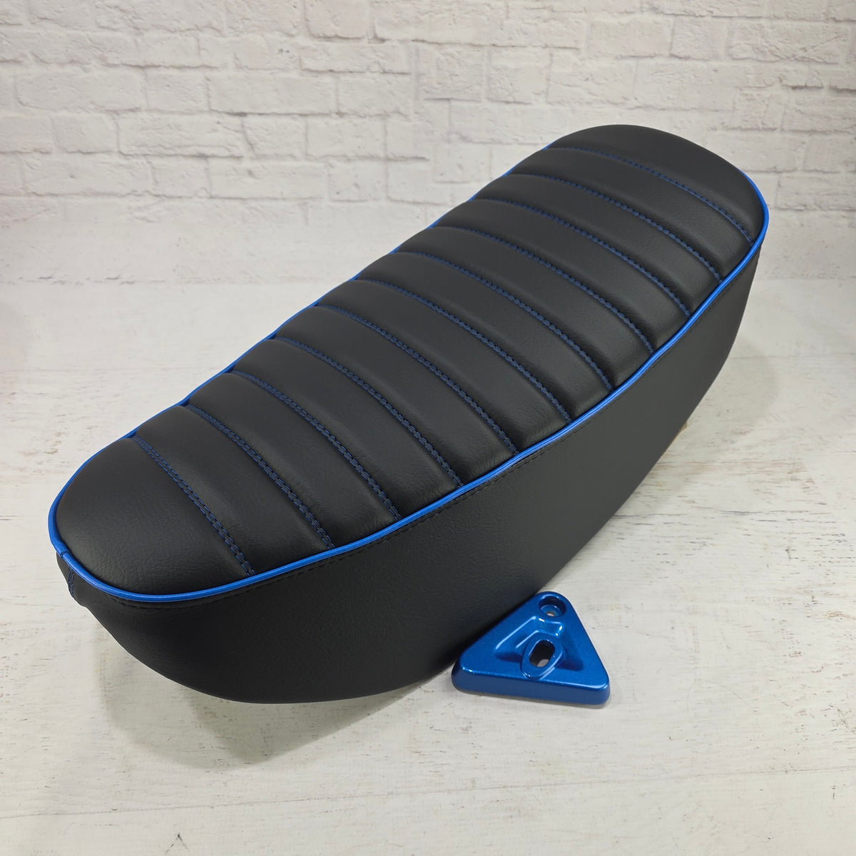 Black double-stitched Honda DAX 125 tuck-and-roll cover with vivid blue piping and matching mounting bracket,  handmade by Cheeky Seats