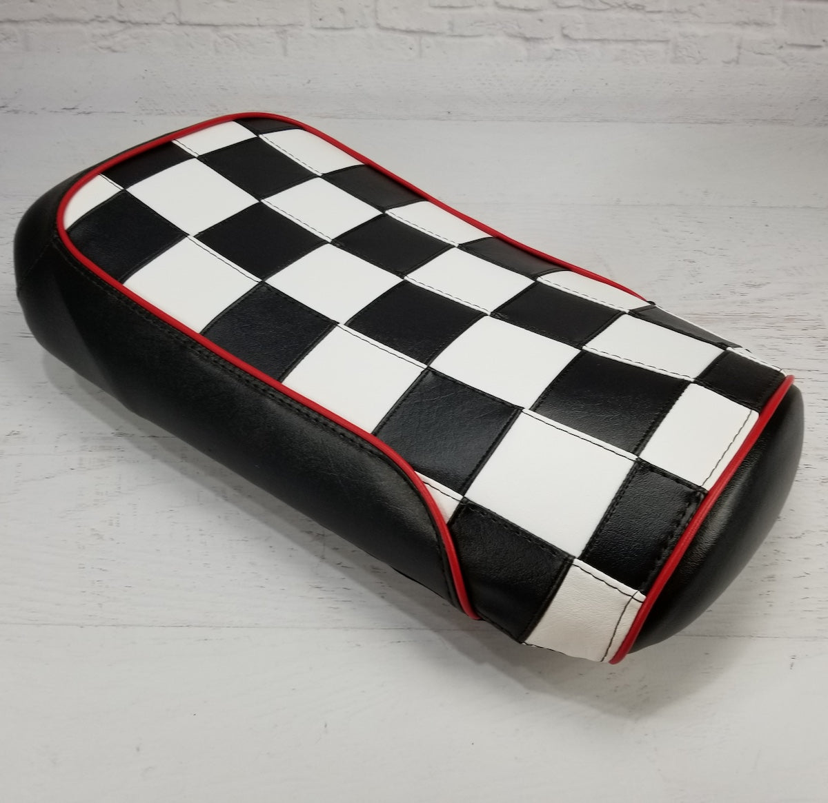Black and white checkerboard Maddog seat cover with red piping and black side panels, three-quarter view, handmade by Cheeky Seats