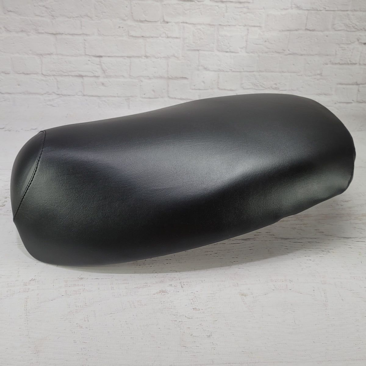 Side profile of the ready-to-ship black Yamaha Vino 125 seat cover showing its clean fit and smooth finish, handmade by Cheeky Seats.