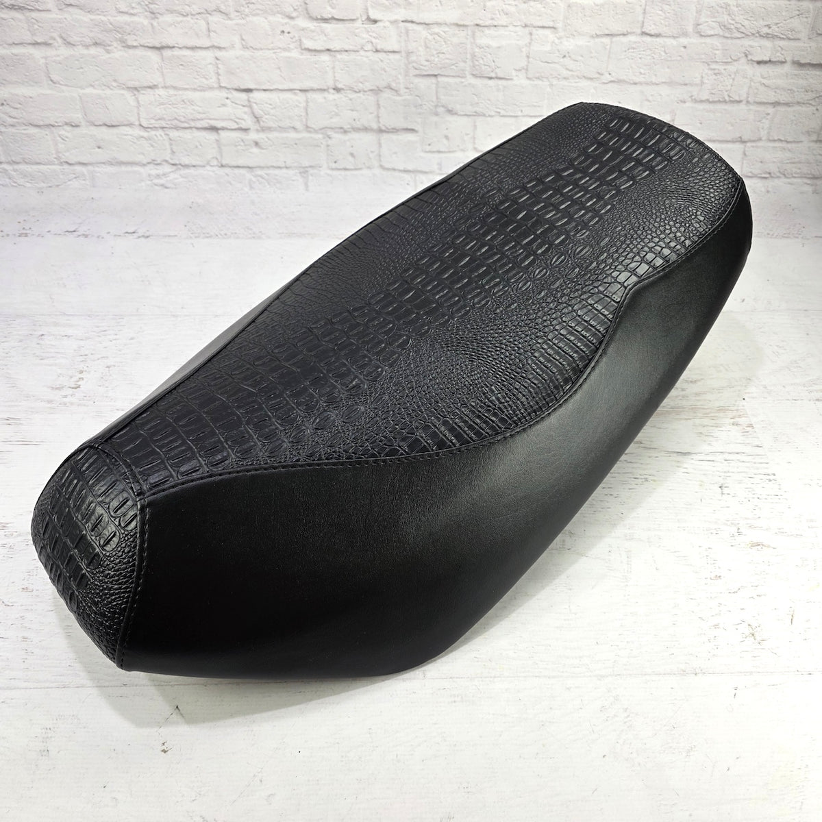 Angled side view of the black Croc and Gator Yamaha Zuma 50 seat cover showing its textured top and fitted panels, handmade by Cheeky Seats.