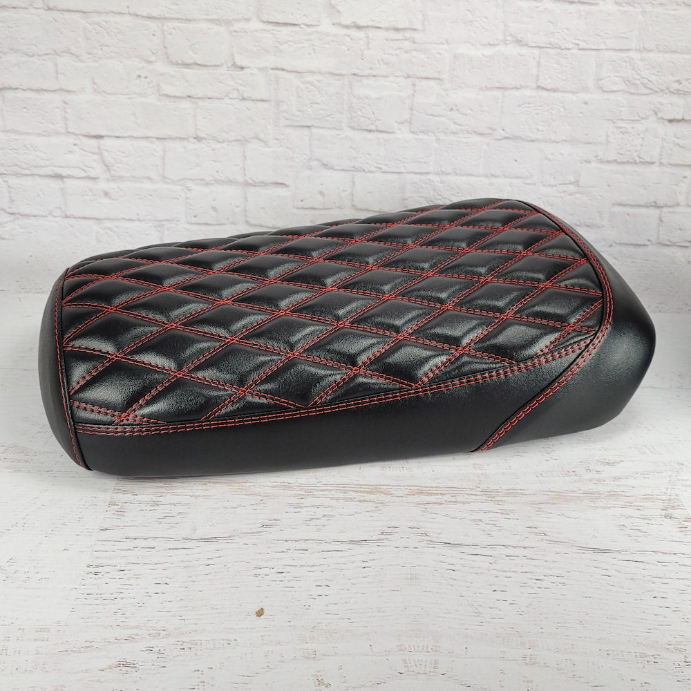 Side view of the satin black diamond seat cover with red stitching, showing the glossy sheen and smooth black side panels, handmade by Cheeky Seats